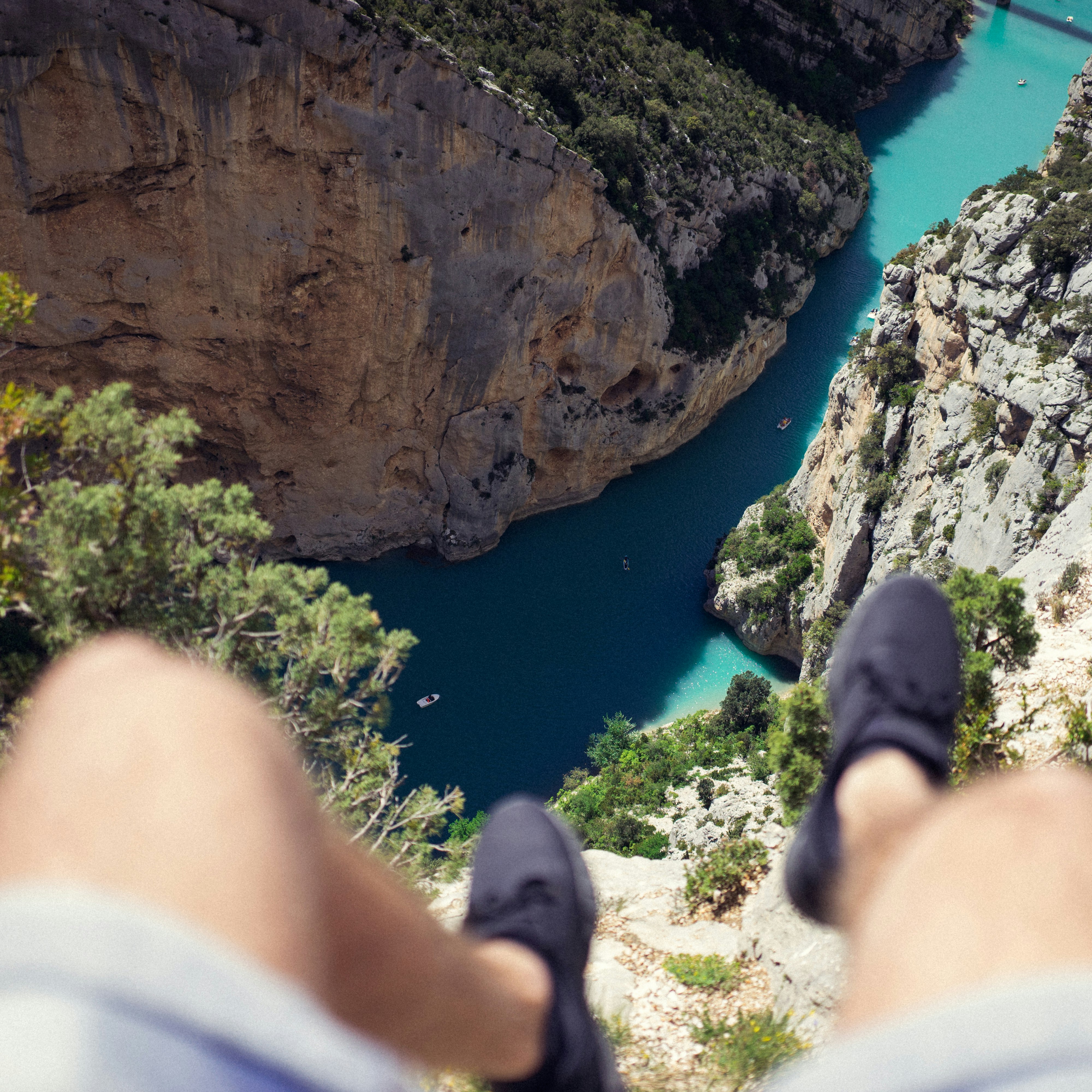 person seating on cliff above body of water